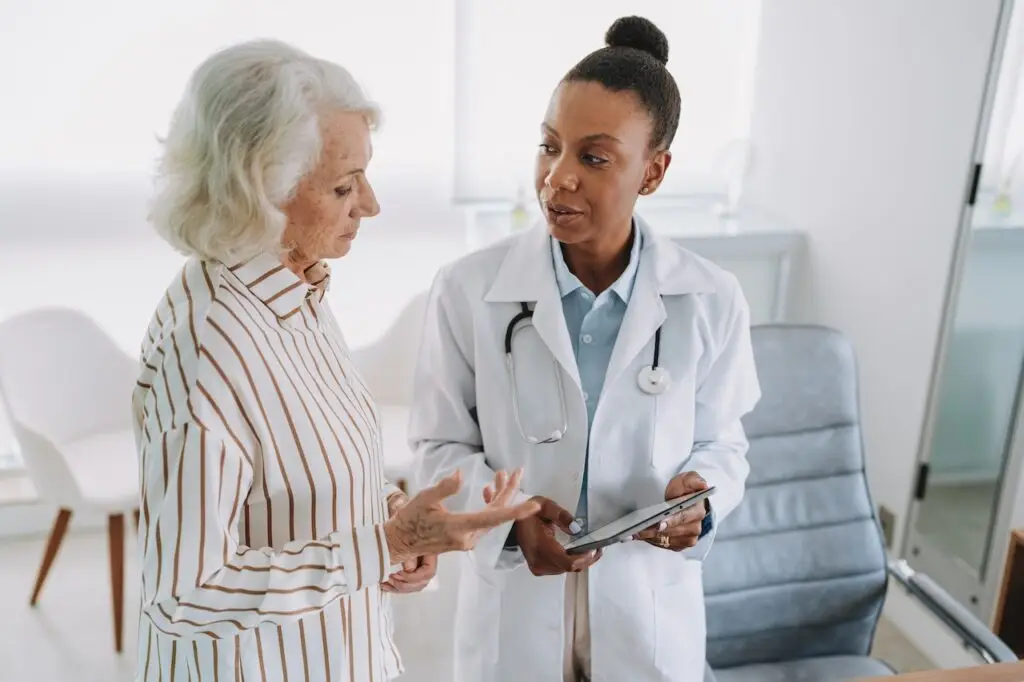 Doctor showing tablet to senior female patient