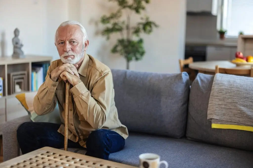Close up of a senior man with beard at home in the living room looking away