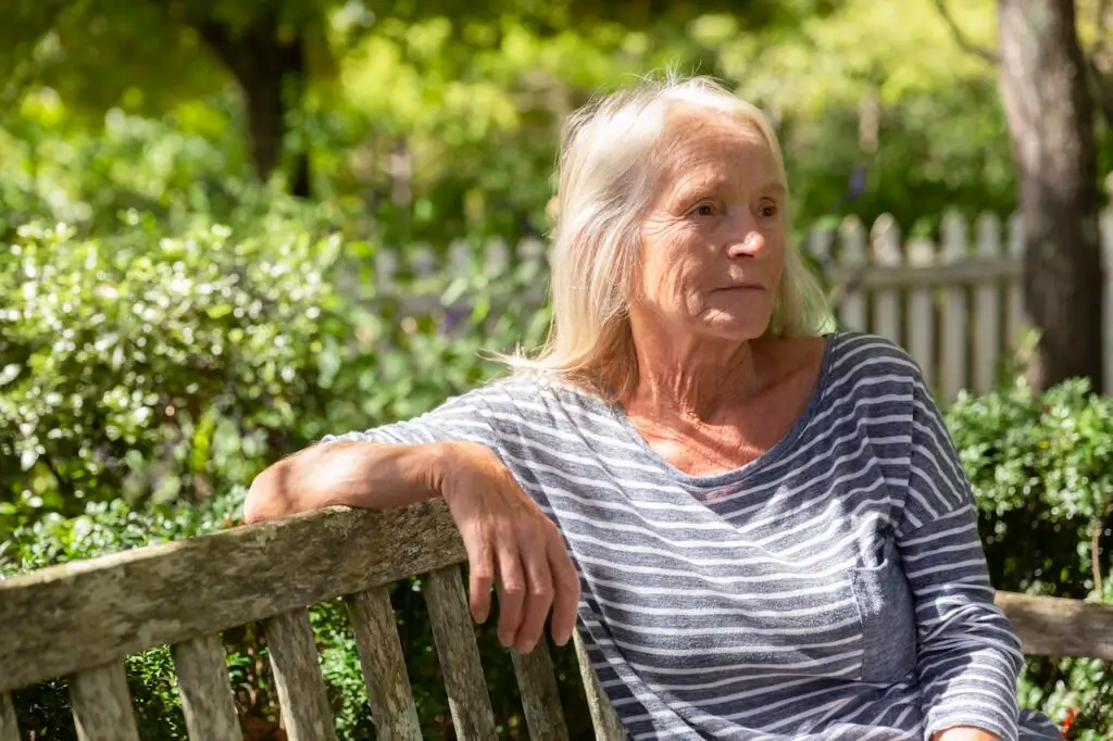 older woman sitting in garden gazing out