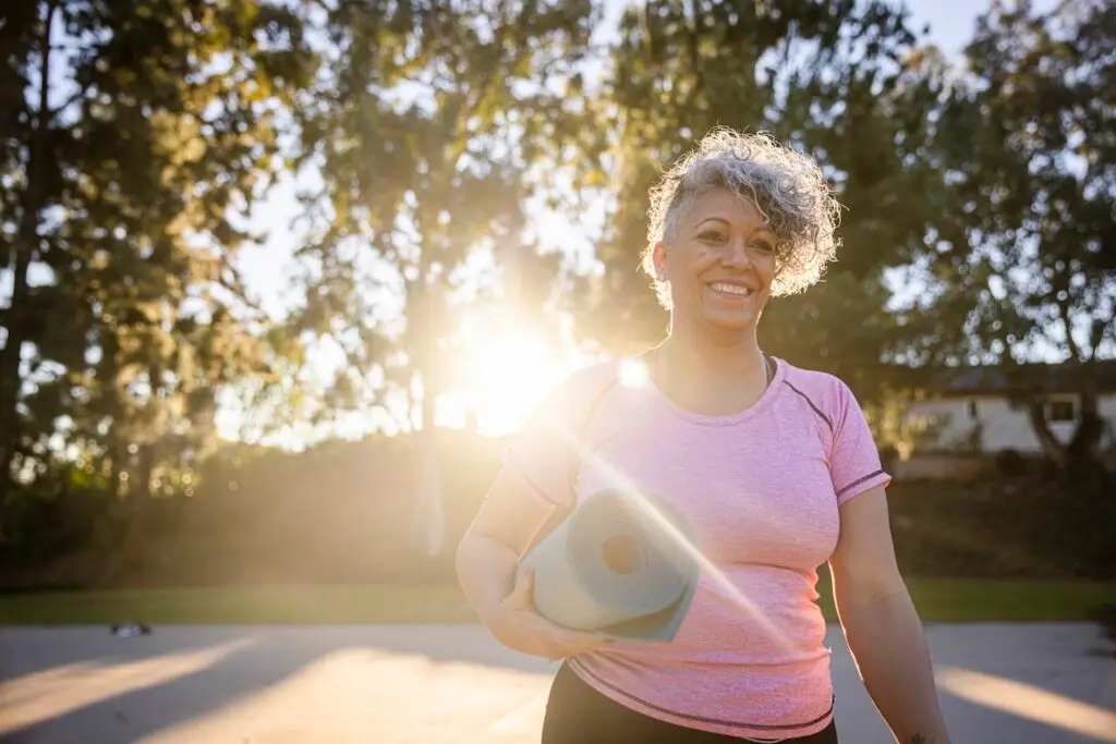 woman holding a yoga mat walking outside