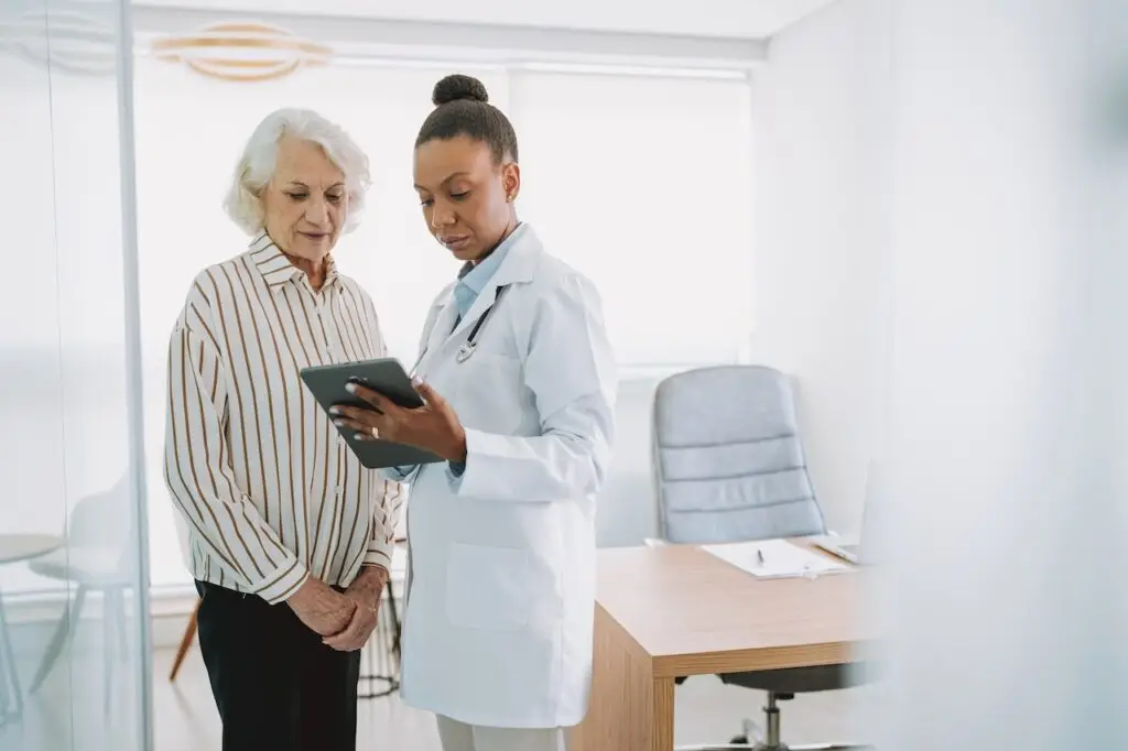 Doctor showing tablet to senior female patient