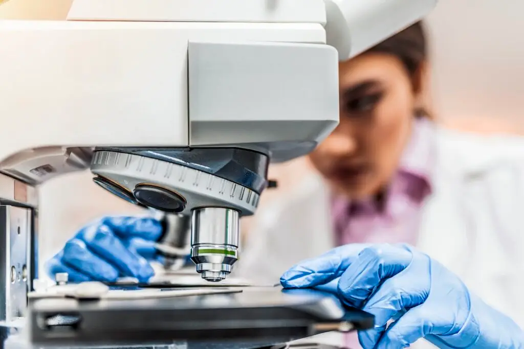 woman scientist examining slide under microscope lab