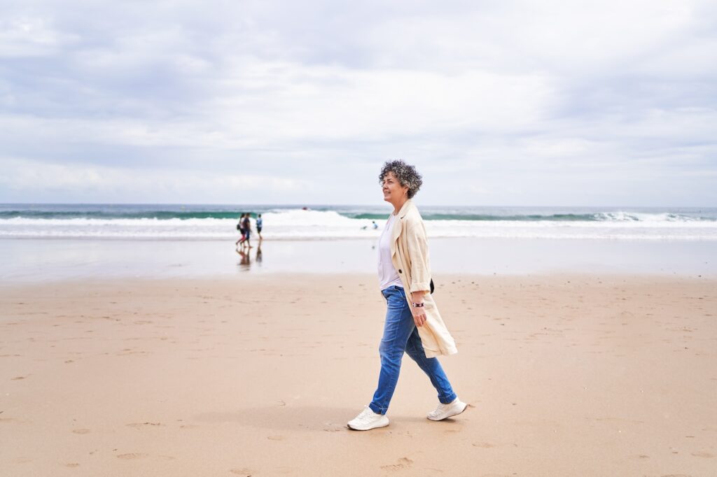 Side view of a woman walking on the beach in casual clothes