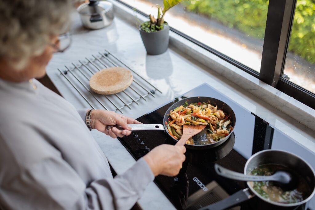 elderly woman making a meal in kitchen at home.