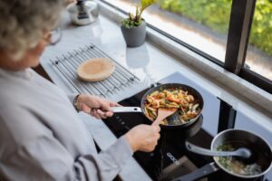 elderly woman making a meal in kitchen at home.