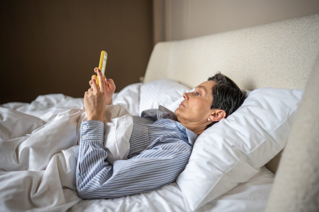 woman scrolling on her phone in bed at home