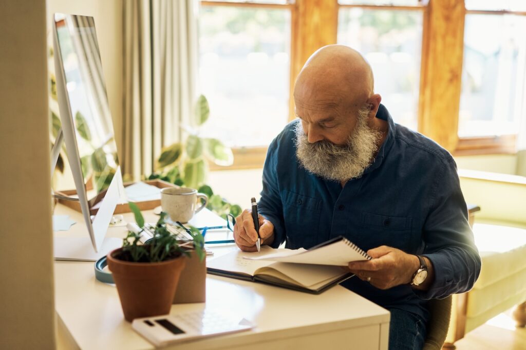 Mature man writing in a notebook diary