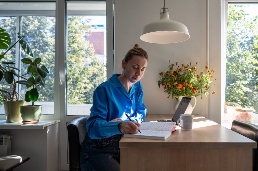 woman sitting in kitchen writing in a notebook