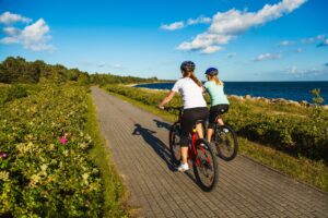 women riding bikes on bike path next to ocean