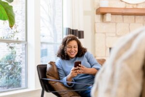 woman sitting in living room scrolling on mobile phone