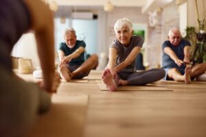 Group of older people doing stretching exercises in a yoga studio