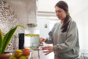 woman dispensing water with lemon on kitchen counter
