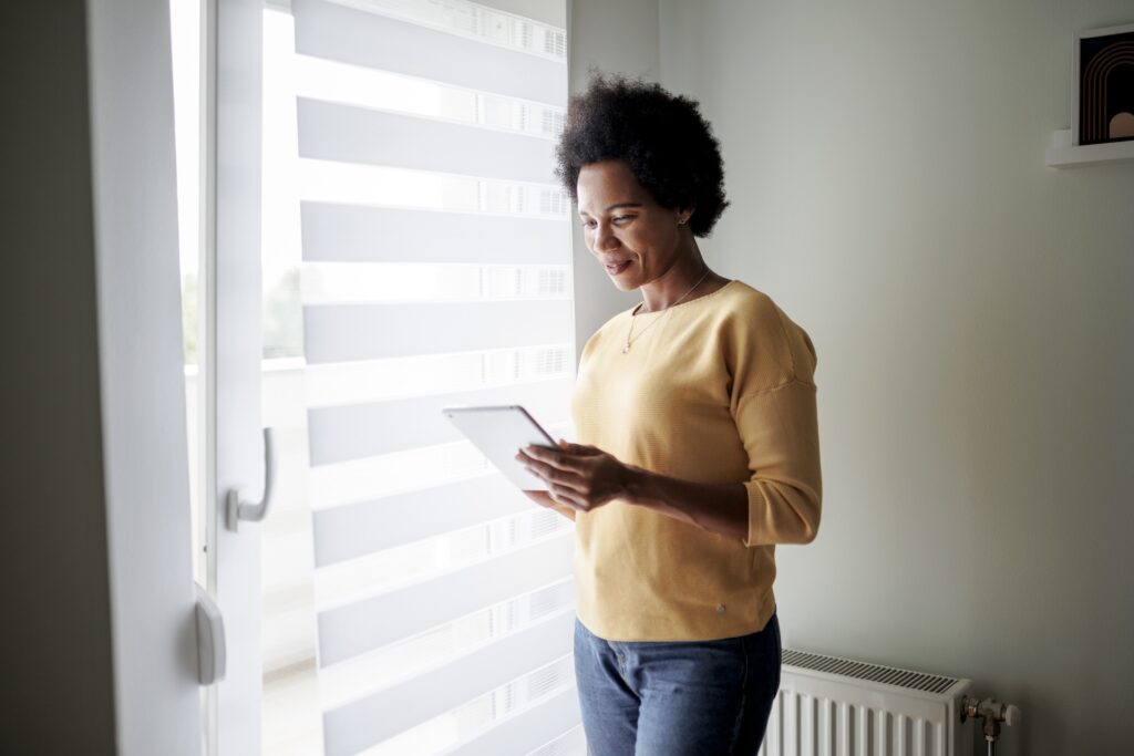 a woman looking at her phone next to a window
