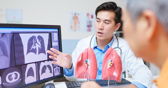 Doctor and patient view lung scan on computer monitor.