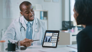 Female Patient Listens to Experienced Pulmonologist Uses Digital Tablet Computer to Show, Explain Lung Analysis Results