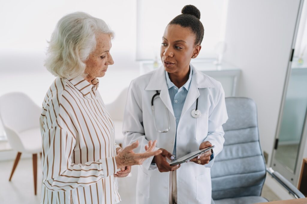 Doctor showing tablet to senior female patient