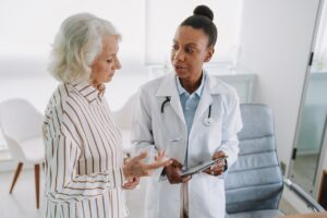Doctor showing tablet to senior female patient