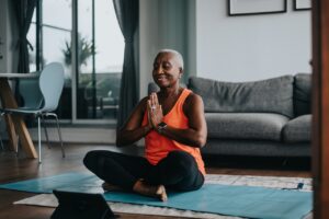 Active black senior woman meditating during at home yoga practice