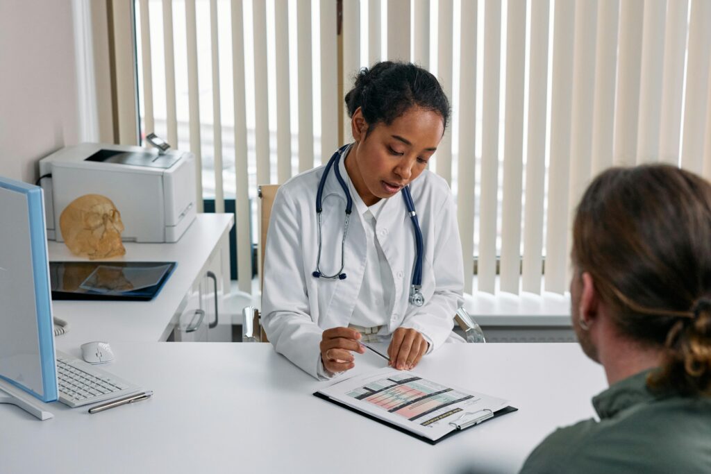 Female doctor and male patient sitting across from each other at desk in office discussing treatment options.