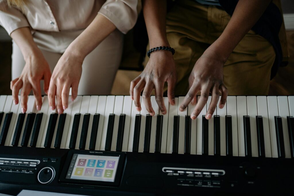two people sitting on bench playing piano