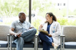 doctor sits with a patient with a notepad in a clinic