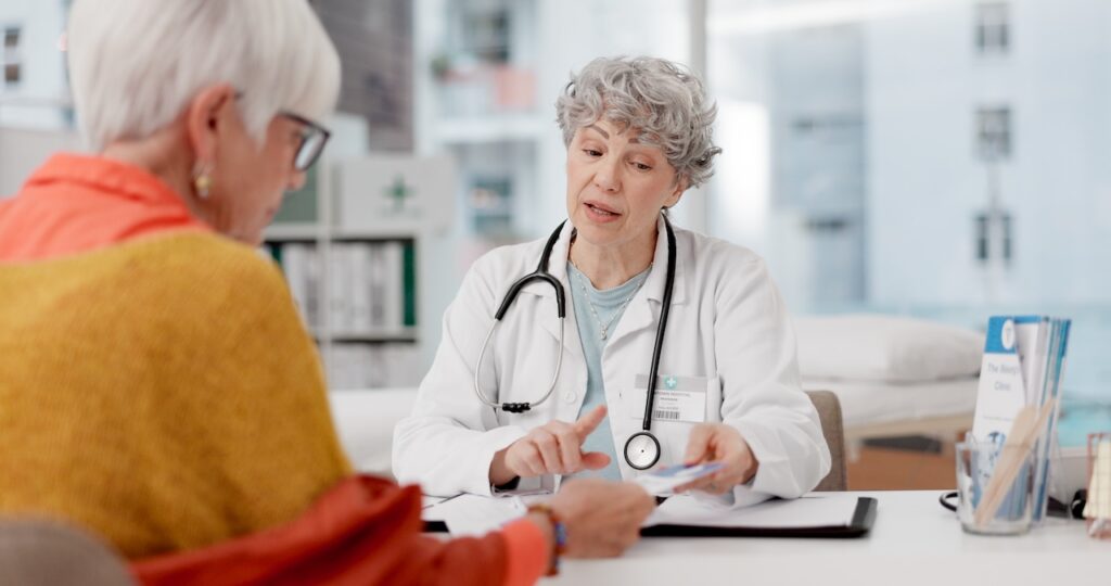 Senior woman, doctor and consulting patient with pamphlet for information, quotation or service at hospital. Mature medical professional talking and explaining healthcare