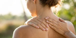Woman touching her upper back because of shoulder blade pain.