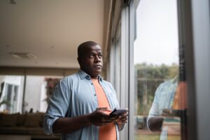 Man contemplating holding a smartphone at home