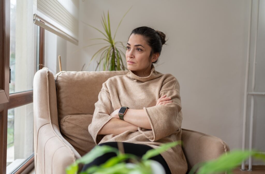Woman Sitting On Armchair By Window And looking outside
