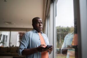 Man contemplating holding a smartphone at home