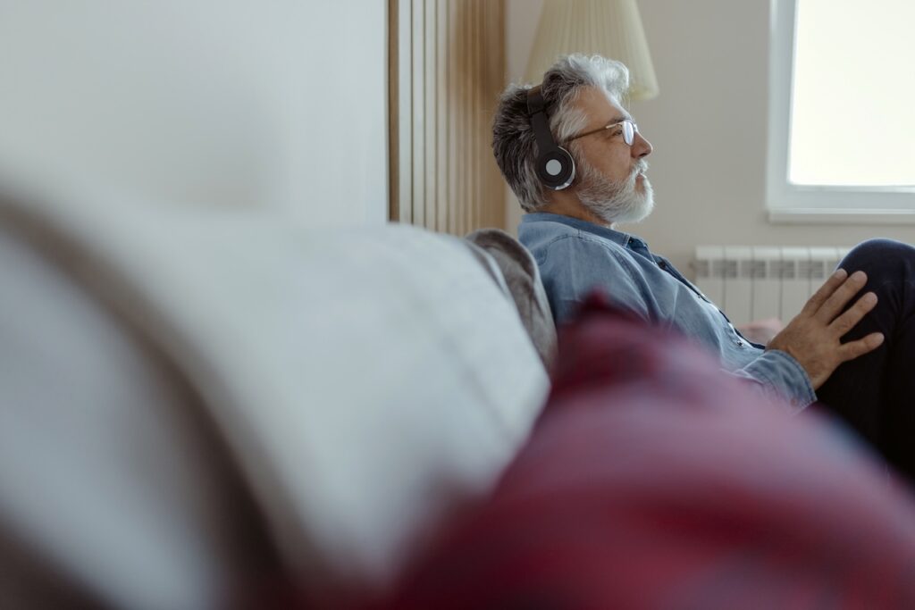 Man at home on sofa listening with headphones