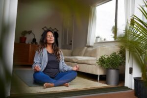 woman meditating while practicing yoga in her living room