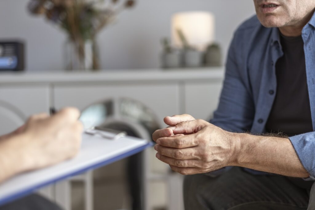 close up of healthcare professional with clipboard speaking to male patient
