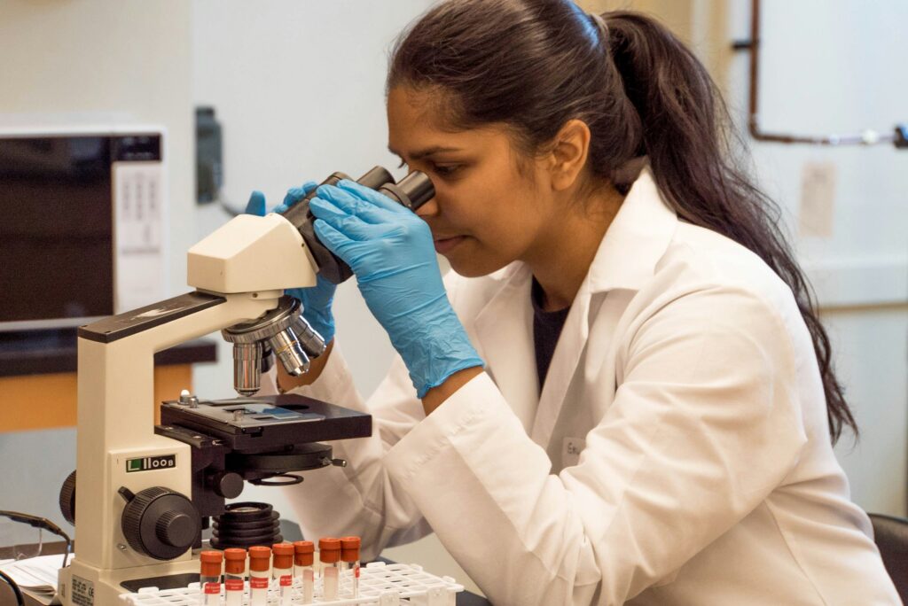 woman in medical lab looking into microscope