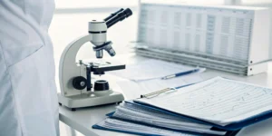 A microscope sits next to a cancer pathology report that a patient is learning how to read.