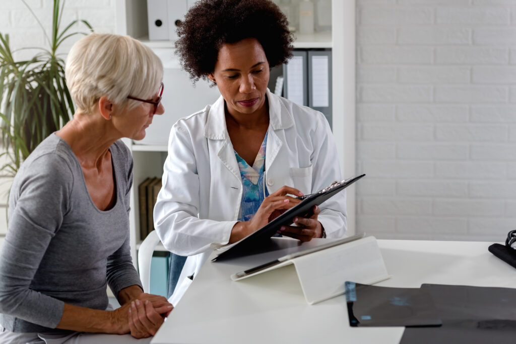 doctor sits at her desk and chats to an female patient while looking at her test results