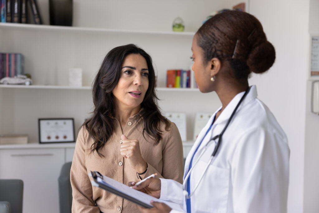 Physician filling medical form, listening to patient in clinic office