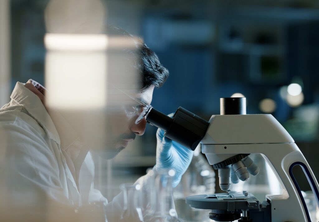 Doctor, microscope and analysis in lab for medical study