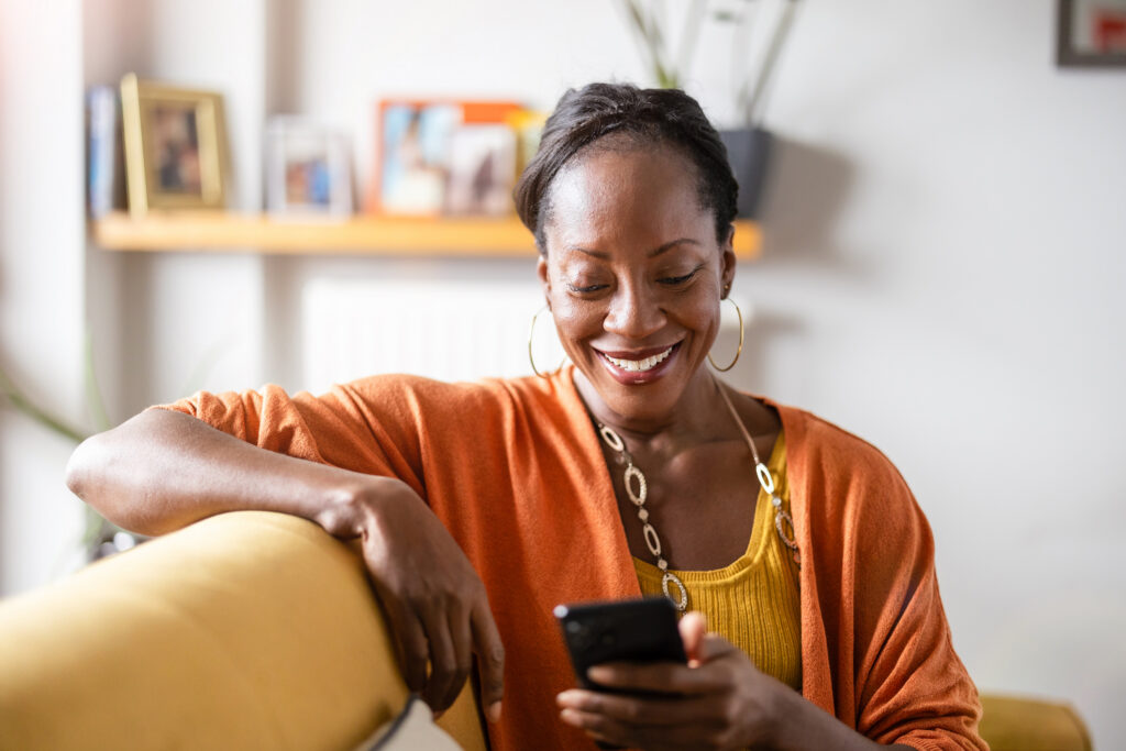woman using mobile phone while relaxing on a sofa at home