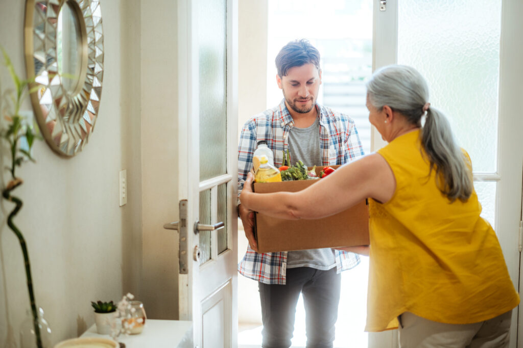 man dropping off groceries at woman's home in the doorway