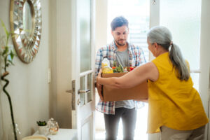 man dropping off groceries at woman's home in the doorway