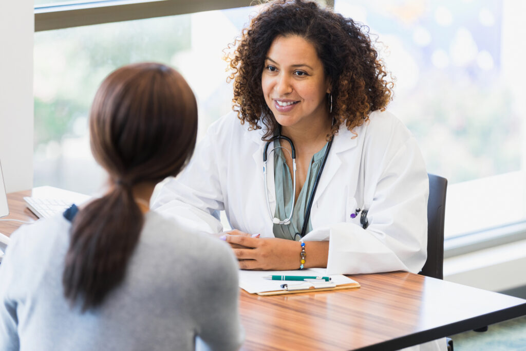 Mid adult female doctor listens attentively to unrecognizable female patient