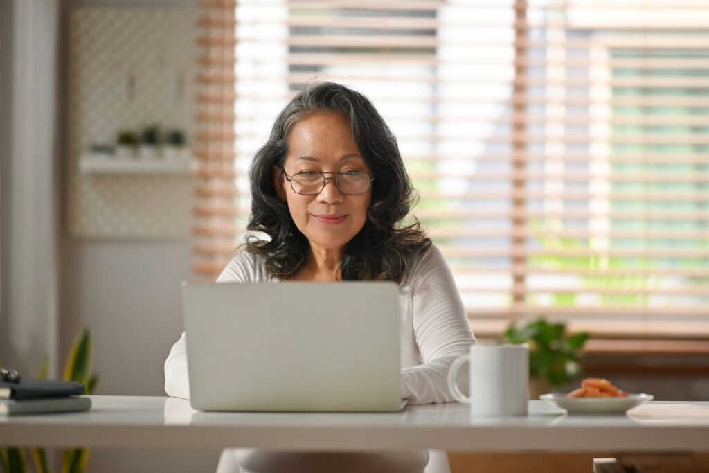 female in glasses watching webinar or checking email on laptop computer at home.