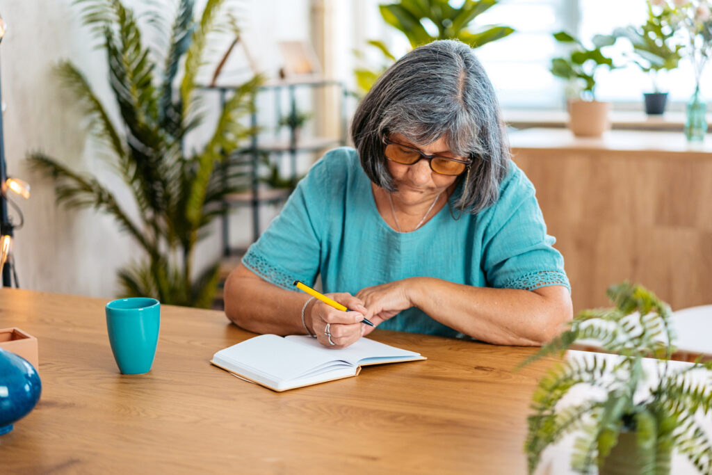 woman writing in a notebook at the kitchen table at home