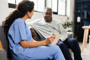 Nurse holding notebook while talking with senior man
