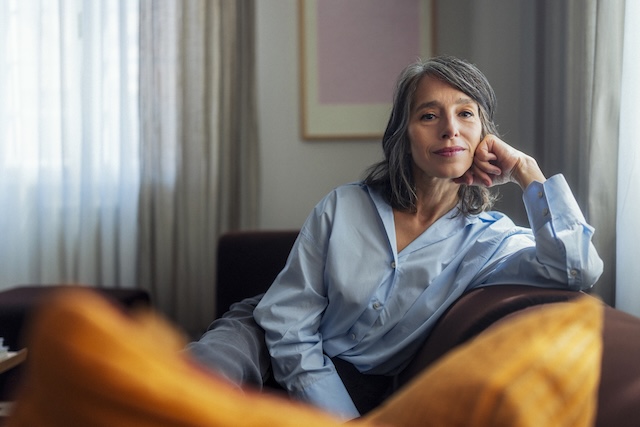 Woman sitting on the couch with her face in her hand, staring at the camera