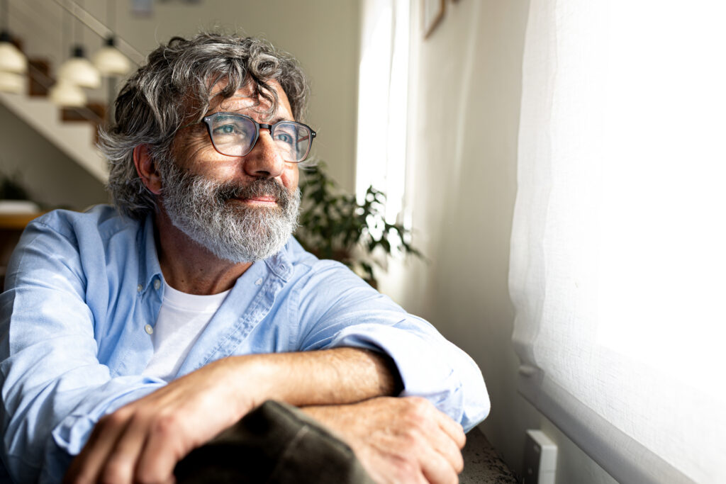 man relaxing and looking out the window at home