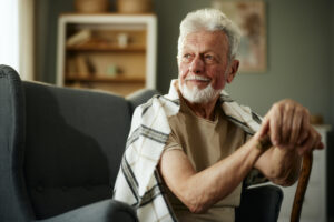 Thoughtful senior man with walking cane relaxing at home