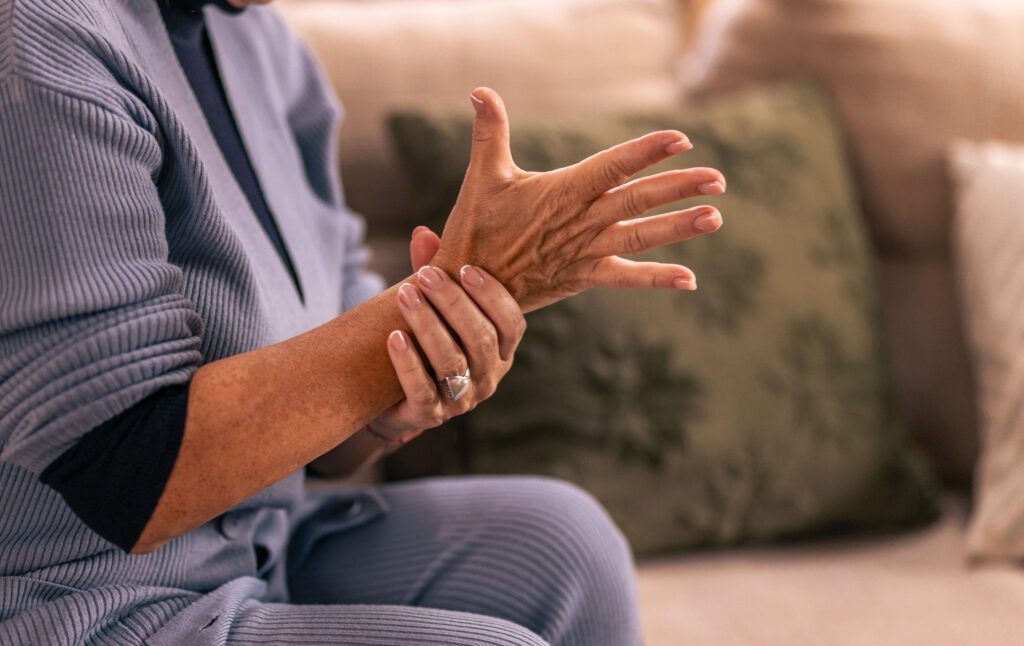 senior woman experiencing hand pain tingling at home